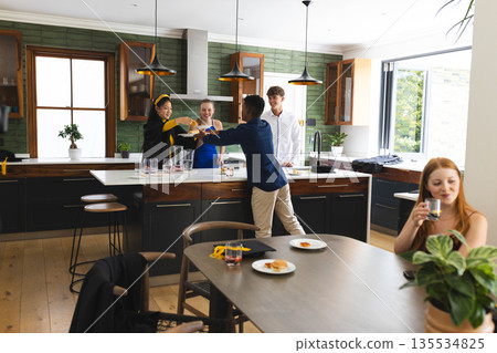 Teens celebrating in modern kitchen, enjoying drinks and laughter together Teens celebrating in modern kitchen, enjoying drinks and laughter together 135534825