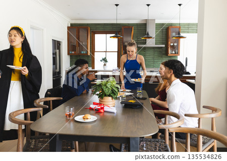 Teens enjoying lively celebration at home, sharing food and laughter around table 135534826