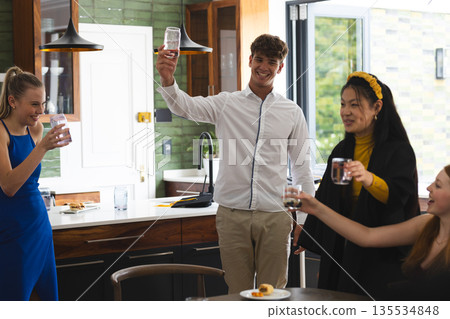 Teens celebrating at home, raising glasses and smiling joyfully together Teens celebrating at home, raising glasses and smiling joyfully together 135534848