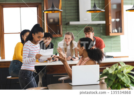 Teen girl excitedly sharing news with friends in modern kitchen setting Teen girl excitedly sharing news with friends in modern kitchen setting 135534868