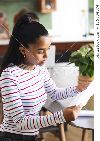 African American teen reading document at home, concentrating on important details African American teen reading document at home, concentrating on important details 135534874