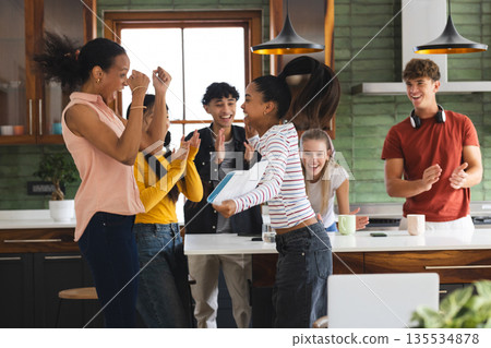 Teenagers celebrating success in kitchen, smiling and clapping with excitement Teenagers celebrating success in kitchen, smiling and clapping with excitement 135534878