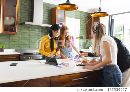In modern kitchen, teen friends collaborating on creative project, sharing ideas enthusiastically In modern kitchen, teen friends collaborating on creative project, sharing ideas enthusiastically 135534927