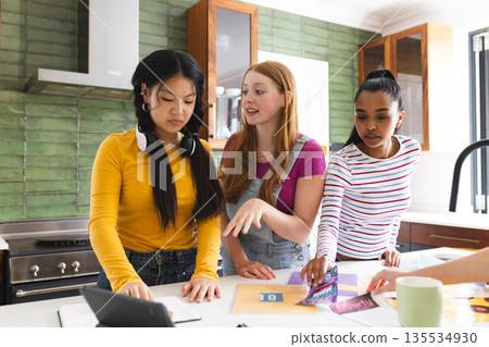 In kitchen, teen girls preparing school project, discussing ideas enthusiastically 135534930