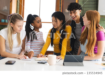 Teen friends collaborating on school project at home, using tablet and notes 135534945