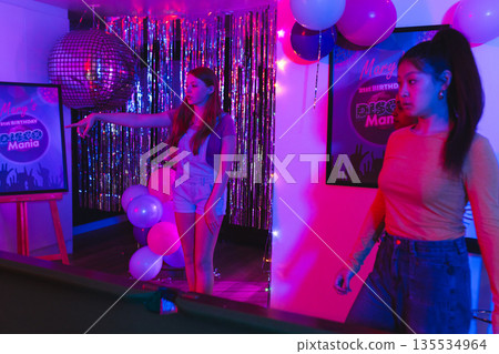 Teen girls enjoying disco-themed birthday party with vibrant lights and decorations Teen girls enjoying disco-themed birthday party with vibrant lights and decorations 135534964