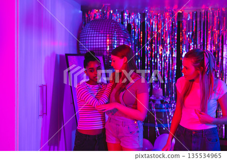 Teen girls celebrating at home with disco ball and shimmering decorations 135534965
