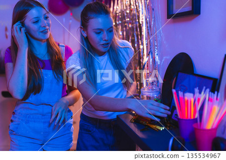 Teen girls enjoying party snacks and drinks in vibrant celebration setting Teen girls enjoying party snacks and drinks in vibrant celebration setting 135534967