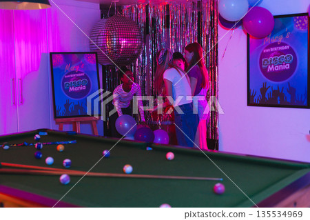 Decorating party room with balloons, teenagers creating disco theme for birthday event Decorating party room with balloons, teenagers creating disco theme for birthday event 135534969