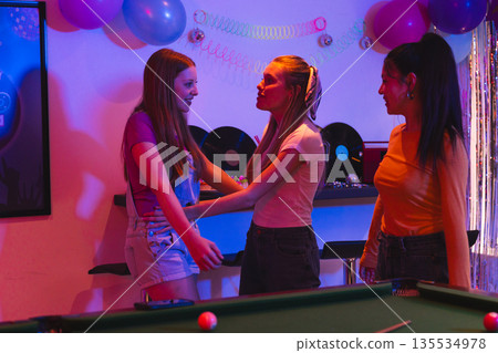 Teen girls enjoying lively birthday party with pool table and colorful decorations Teen girls enjoying lively birthday party with pool table and colorful decorations 135534978