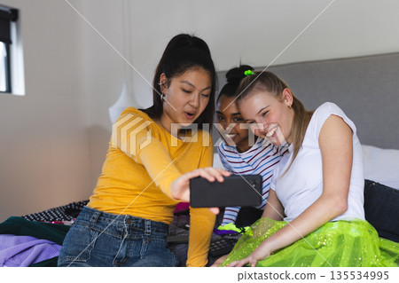 Teen girls taking selfie on bed, smiling and enjoying fun moments together Teen girls taking selfie on bed, smiling and enjoying fun moments together 135534995