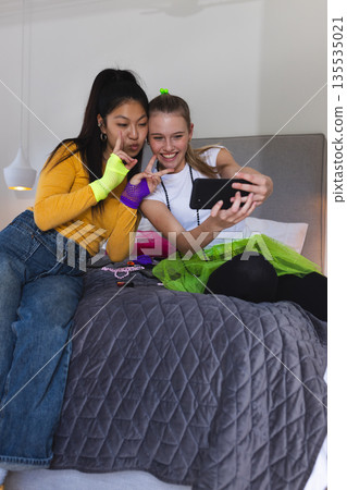 Teen girls taking selfie on bed, smiling and enjoying fun moments together Teen girls taking selfie on bed, smiling and enjoying fun moments together 135535021