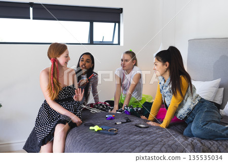 Teen girls sitting on bed chatting and enjoying time together at home 135535034