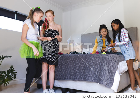 Teen girls choosing outfits together in bedroom, enjoying fun fashion moments Teen girls choosing outfits together in bedroom, enjoying fun fashion moments 135535045