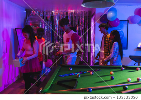 Teenagers enjoying vibrant birthday party with pool table and festive decorations Teenagers enjoying vibrant birthday party with pool table and festive decorations 135535050