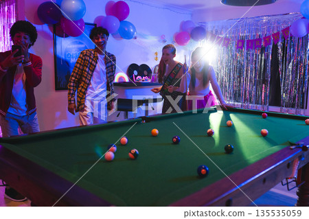 Teens celebrating birthday playing pool in festive room with colorful balloons Teens celebrating birthday playing pool in festive room with colorful balloons 135535059