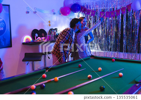 Teens taking selfie at birthday party near pool table with festive decorations 135535061