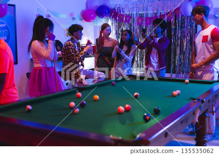 Teenagers celebrating birthday with pool table and decorations at home party Teenagers celebrating birthday with pool table and decorations at home party 135535062