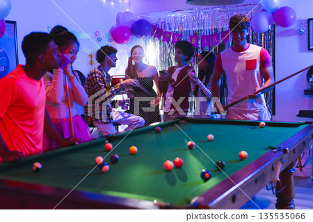 Teenagers enjoying lively birthday party playing pool in festive decorated room 135535066