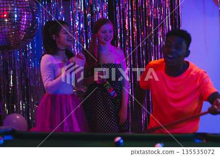 Teens enjoying lively birthday party with pool table and disco ball Teens enjoying lively birthday party with pool table and disco ball 135535072