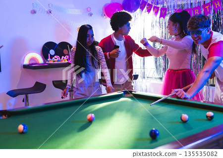 Teenagers playing pool and celebrating birthday in colorful party room Teenagers playing pool and celebrating birthday in colorful party room 135535082