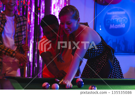 Teenagers playing pool at birthday party, enjoying lively celebration atmosphere Teenagers playing pool at birthday party, enjoying lively celebration atmosphere 135535086