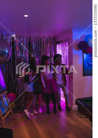 Teens celebrating at home with balloons and disco ball, enjoying party together Teens celebrating at home with balloons and disco ball, enjoying party together 135535090