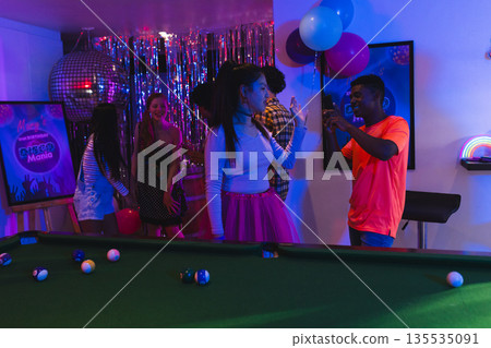 Teenagers dancing and celebrating party at home with balloons and pool table Teenagers dancing and celebrating party at home with balloons and pool table 135535091