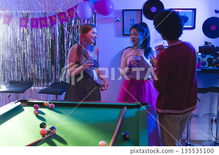 Teen friends celebrating birthday with drinks and laughter around pool table Teen friends celebrating birthday with drinks and laughter around pool table 135535100