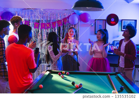Celebrating birthday with cake and balloons, teenagers around pool table smiling joyfully Celebrating birthday with cake and balloons, teenagers around pool table smiling joyfully 135535102