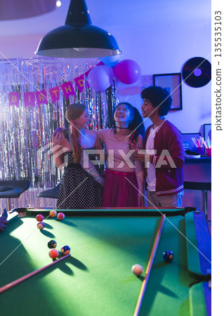 Teenagers celebrating birthday party near pool table, laughing and enjoying together Teenagers celebrating birthday party near pool table, laughing and enjoying together 135535103