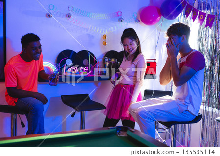 Teen friends laughing and celebrating at home with colorful party decorations 135535114