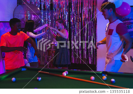 Teenagers dancing joyfully at party with pool table and disco ball Teenagers dancing joyfully at party with pool table and disco ball 135535118
