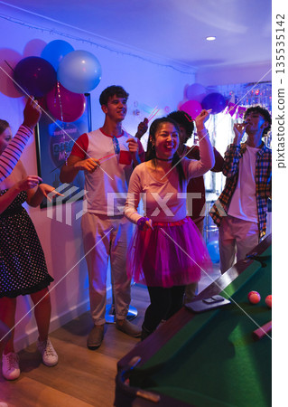 Teenagers celebrating at home, dancing and enjoying lively party atmosphere Teenagers celebrating at home, dancing and enjoying lively party atmosphere 135535142