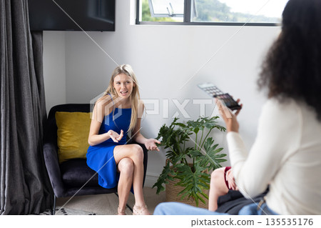 Teen girl in blue dress expressing surprise while friend takes photo at home Teen girl in blue dress expressing surprise while friend takes photo at home 135535176