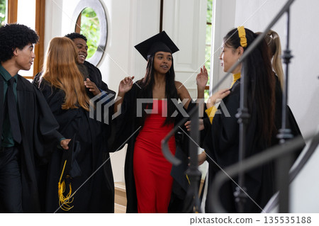 Graduating students in caps and gowns celebrating together at home 135535188