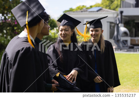 Graduating students in caps and gowns celebrating outdoors with joyful smiles Graduating students in caps and gowns celebrating outdoors with joyful smiles 135535237