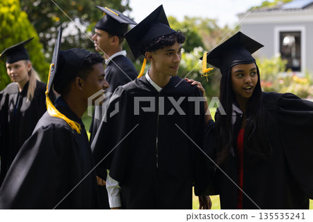 Graduating students in caps and gowns celebrating together outdoors, feeling excited Graduating students in caps and gowns celebrating together outdoors, feeling excited 135535241
