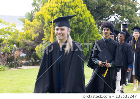 Graduating students in caps and gowns celebrating achievement together outdoors Graduating students in caps and gowns celebrating achievement together outdoors 135535247