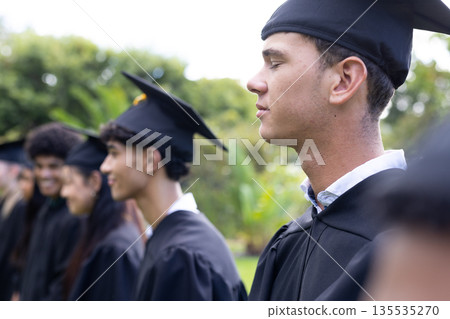 Graduating students in caps and gowns celebrating outdoors with joyful expressions Graduating students in caps and gowns celebrating outdoors with joyful expressions 135535270