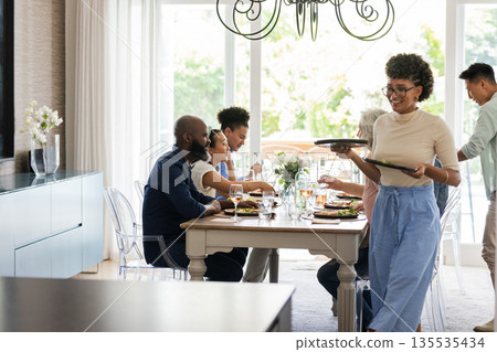 Family enjoying dinner together at home, sharing laughter and conversation Family enjoying dinner together at home, sharing laughter and conversation 135535434