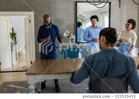 Preparing table for celebration, African American man and friends laughing at home Preparing table for celebration, African American man and friends laughing at home 135535435