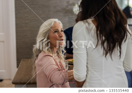 Elderly woman with long hair engaging in lively conversation at wedding reception 135535440