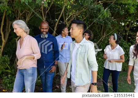 Group of diverse people walking together outdoors, enjoying nature and conversation Group of diverse people walking together outdoors, enjoying nature and conversation 135535441
