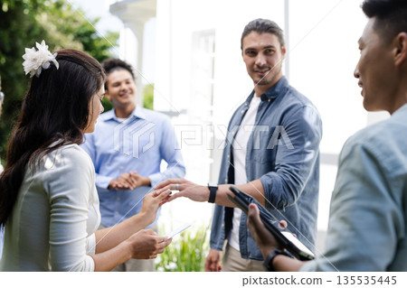 Exchanging smiles and conversations, guests celebrating outdoor wedding in garden setting 135535445