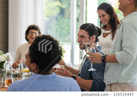 Friends laughing and enjoying drinks together at wedding reception indoors Friends laughing and enjoying drinks together at wedding reception indoors 135535447