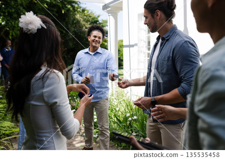 Guests exchanging colorful gifts outdoors, smiling and enjoying wedding celebration Guests exchanging colorful gifts outdoors, smiling and enjoying wedding celebration 135535458