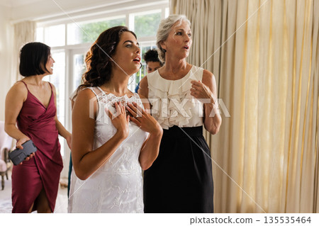 Bride in elegant dress expressing joy with family in beautifully lit room Bride in elegant dress expressing joy with family in beautifully lit room 135535464