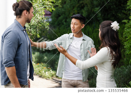 During wedding celebration, Asian man discussing with friends outdoors, sharing joy During wedding celebration, Asian man discussing with friends outdoors, sharing joy 135535466
