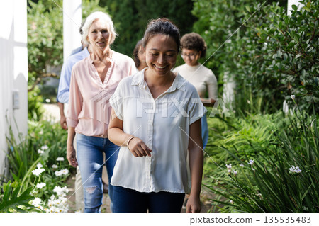 Smiling guests walking through lush garden during wedding celebration outdoors 135535483